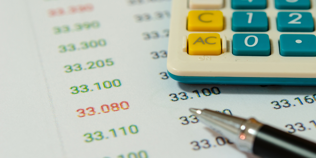 Picture of some financial figures marked in either green on red on paper with a calculator and pen next to it